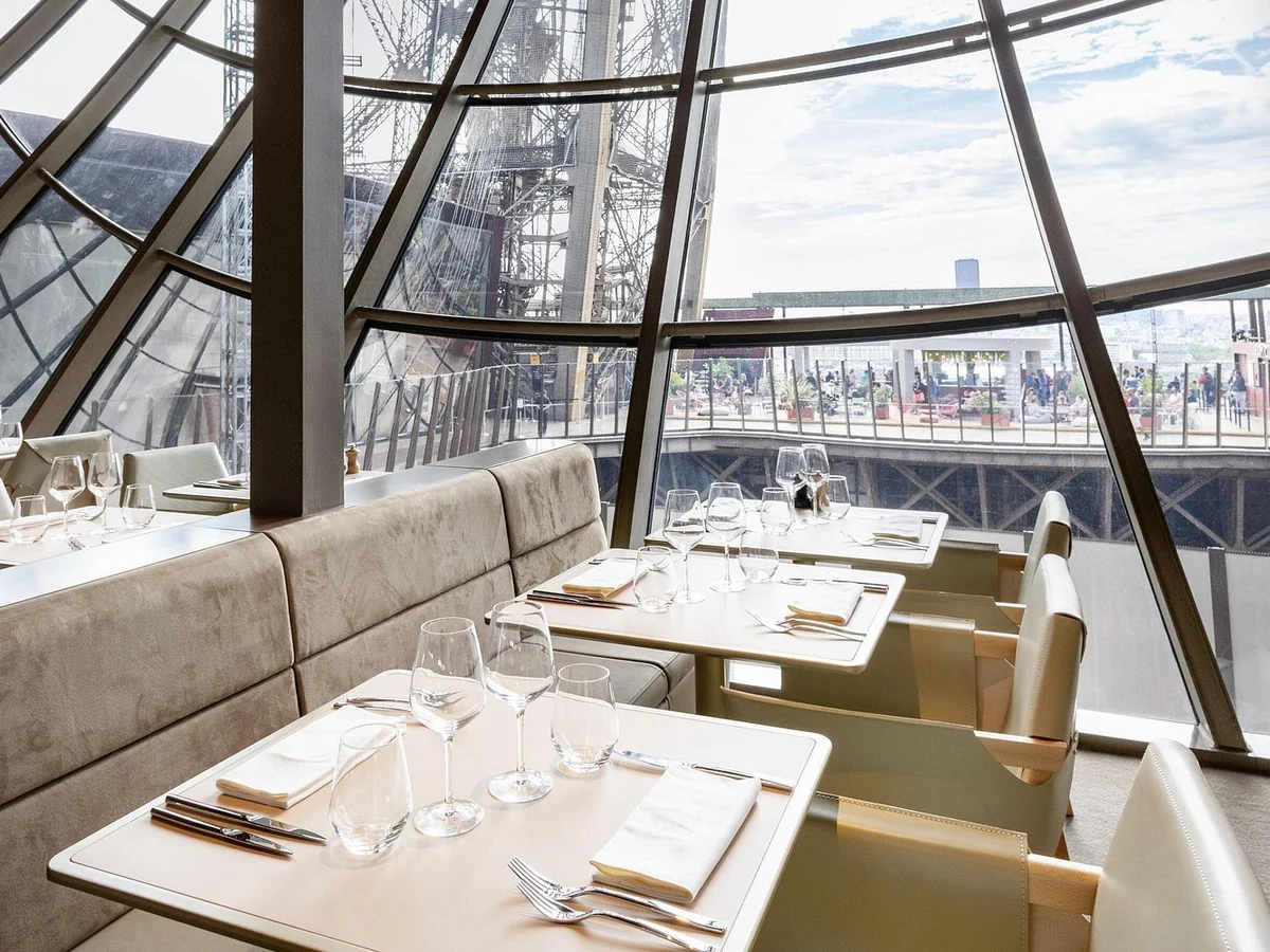 Dining tables beside the Eiffel Tower iron structure inside Madame Brasserie restaurant